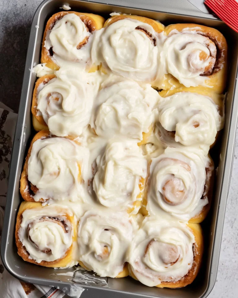 Freshly baked homemade cinnamon rolls topped with cream cheese frosting.