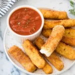 Plate of homemade mozzarella sticks served with marinara sauce