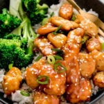 Healthy honey sesame chicken dish served with vegetables and rice.