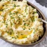 Bowl of creamy garlic mashed potatoes topped with fresh herbs