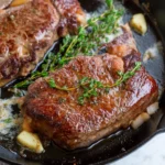 Delicious pan-seared steak topped with garlic butter, served on a plate.