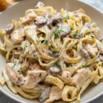 Creamy chicken mushroom pasta dish garnished with parsley and served in a bowl.