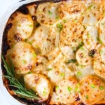 Creamy potato gratin dish topped with cheese and herbs