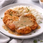 Crispy fried pork chops served on a plate with herbs and spices.