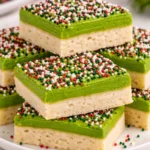 Festive Christmas sugar cookie bars topped with colorful sprinkles on a plate.