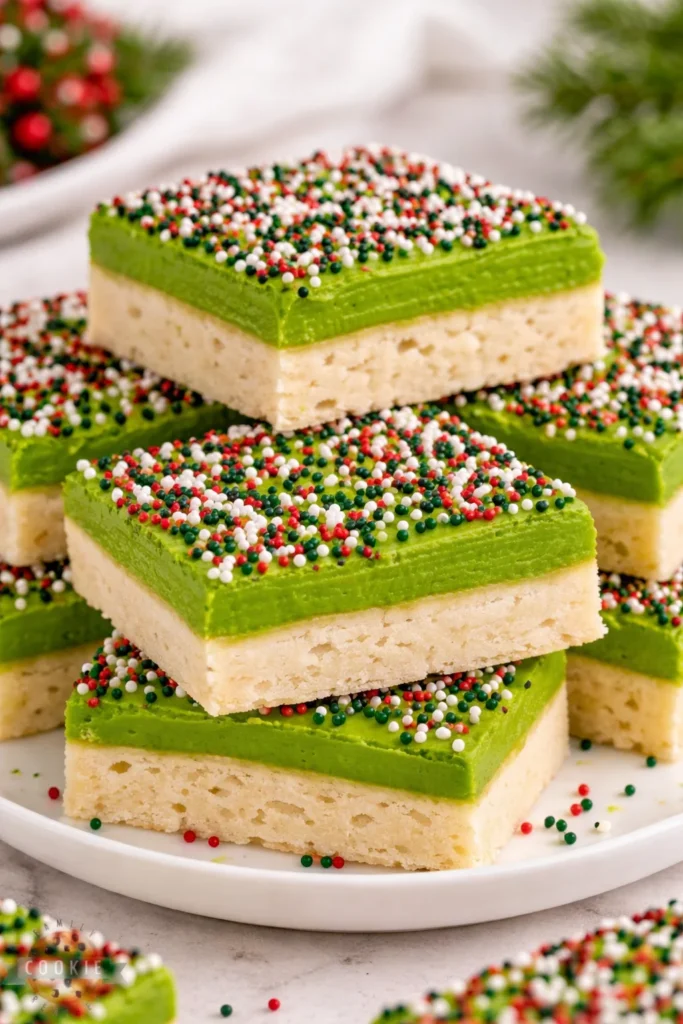 Festive Christmas sugar cookie bars topped with colorful sprinkles on a plate.