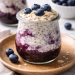 Bowl of blueberry overnight oats topped with fresh blueberries and almonds.