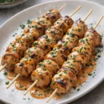 Bang Bang Chicken Skewers with spicy sauce on a grill plate