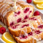 Slice of raspberry lemon loaf with fresh raspberries and lemon on a plate